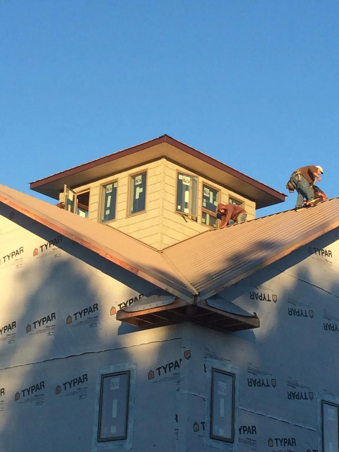 Roofers working around a rooftop cupola on a new metal roof at sunset — Roof Waterproofing in Encinitas by Roofing Brothers